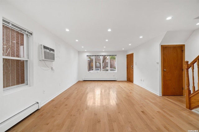 unfurnished living room with light hardwood / wood-style floors, baseboard heating, and a wall mounted AC