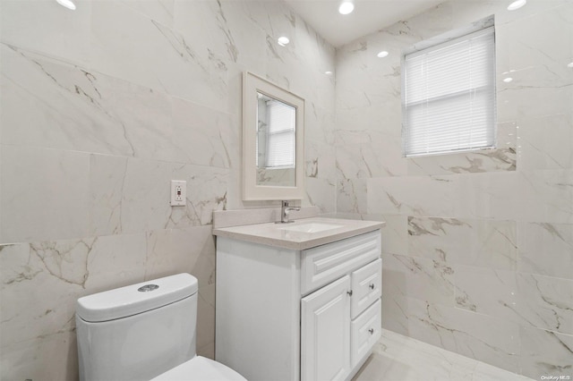 bathroom with vanity, toilet, and tile walls