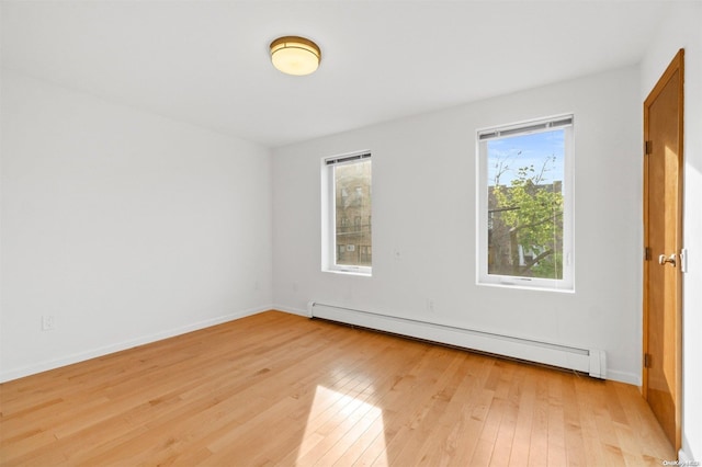 unfurnished room featuring light hardwood / wood-style floors and a baseboard heating unit