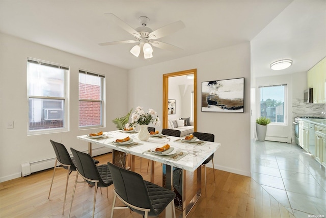 dining room featuring ceiling fan, light wood-type flooring, and a baseboard heating unit