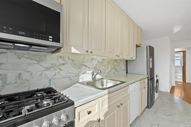 kitchen featuring cream cabinets, sink, light stone countertops, tasteful backsplash, and stainless steel appliances