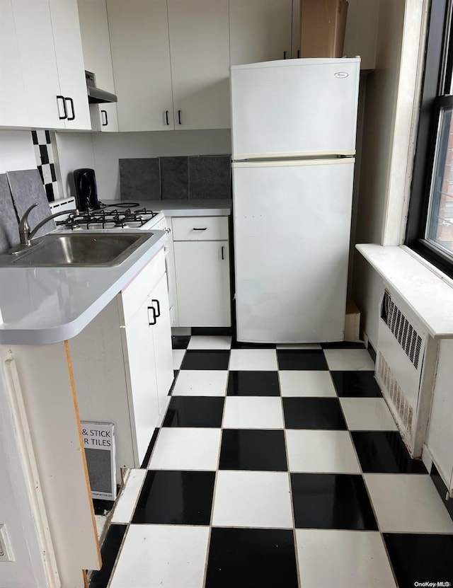 kitchen with decorative backsplash, extractor fan, sink, white cabinets, and white fridge