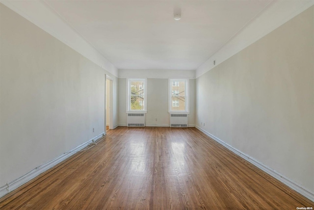 unfurnished room featuring radiator heating unit and hardwood / wood-style flooring