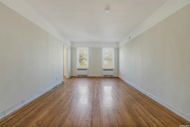 85-10 34th Ave Unit 421, Jackson Heights, NY 11372 - unfurnished room with radiator heating unit, wood finished floors, and baseboards