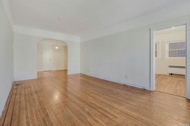 empty room featuring radiator and light hardwood / wood-style flooring