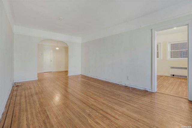 85-10 34th Ave Unit 421, Jackson Heights, NY 11372 - spare room featuring radiator, arched walkways, light wood-style floors, and baseboards