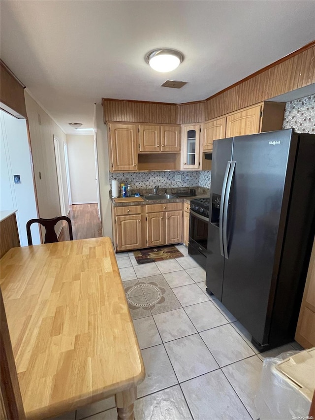 kitchen featuring backsplash, sink, stainless steel fridge, light tile patterned floors, and gas stove