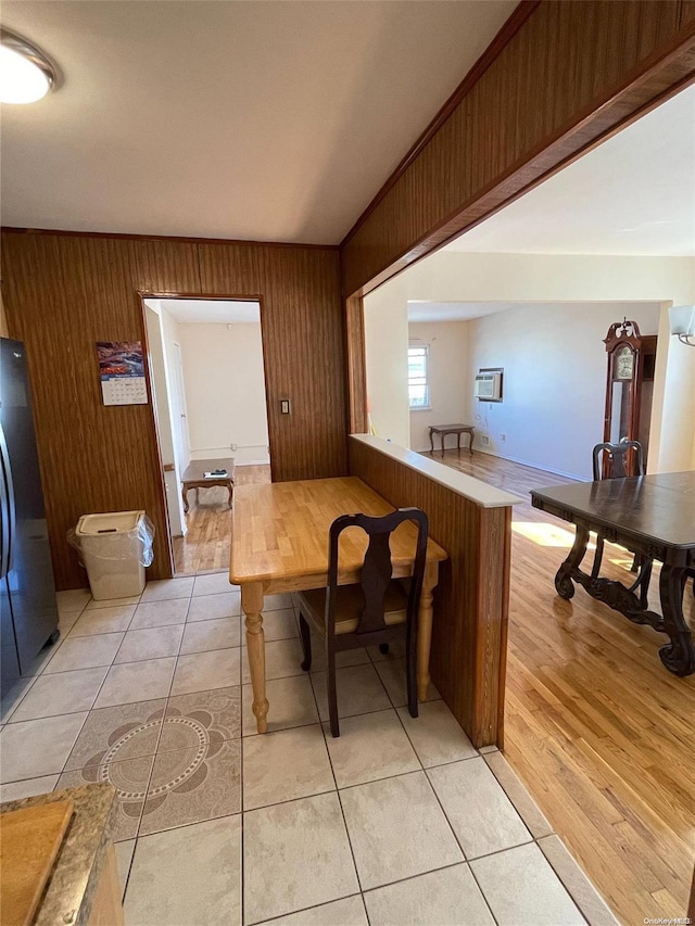 dining room with a wall mounted air conditioner, light wood-type flooring, and wooden walls