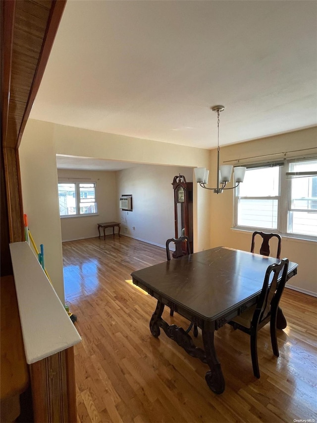 dining room with hardwood / wood-style floors, a healthy amount of sunlight, and a notable chandelier