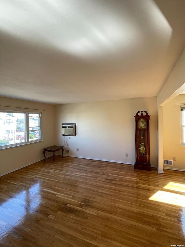 unfurnished living room with vaulted ceiling, a wall mounted AC, and dark wood-type flooring