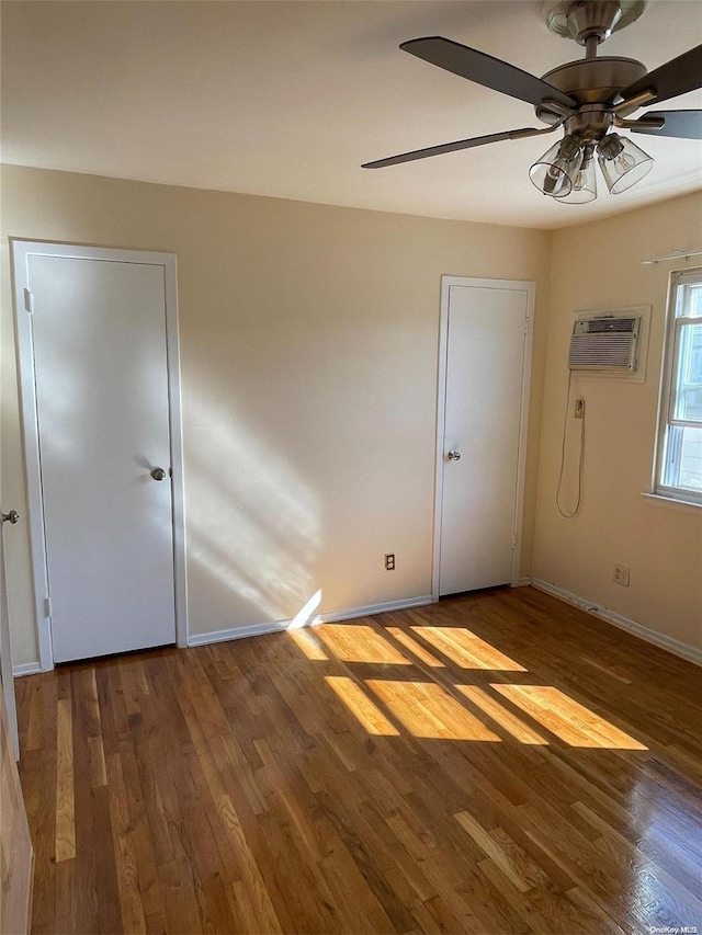 unfurnished room featuring hardwood / wood-style floors, a wall unit AC, and ceiling fan