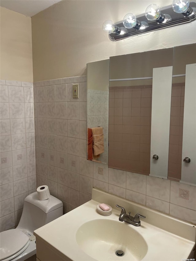 bathroom with vanity, tile walls, and toilet