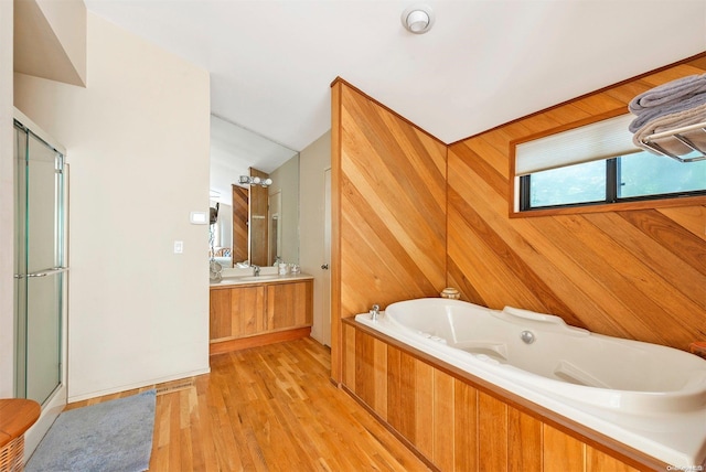 bathroom with vanity, plus walk in shower, hardwood / wood-style floors, lofted ceiling, and wood walls