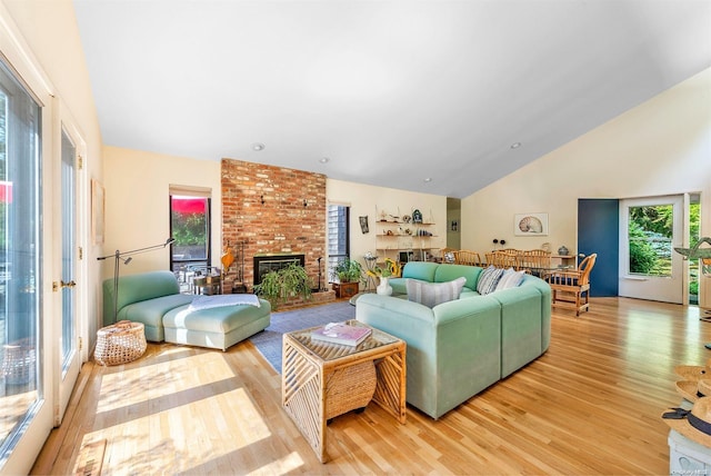 living room featuring a fireplace, light hardwood / wood-style floors, and high vaulted ceiling