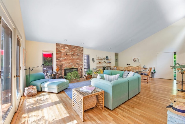 living room featuring a fireplace, high vaulted ceiling, and light wood-type flooring