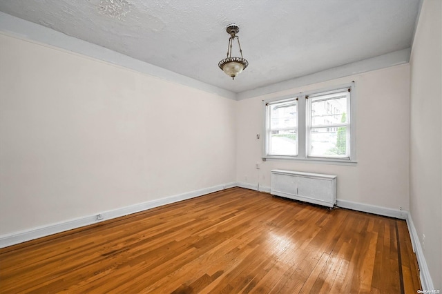 spare room with wood-type flooring, a textured ceiling, and radiator