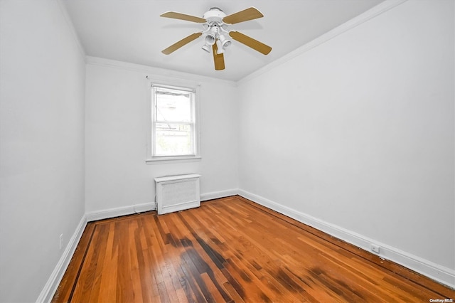 empty room with radiator heating unit, ceiling fan, hardwood / wood-style floors, and ornamental molding