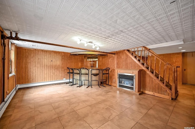 bar with wood walls, a baseboard radiator, and track lighting