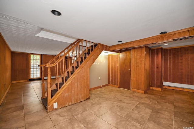 staircase featuring tile patterned floors, baseboard heating, and wooden walls