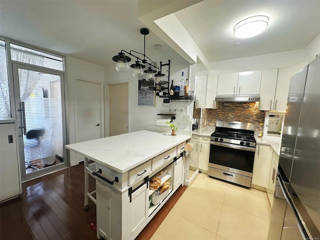 kitchen featuring hanging light fixtures, decorative backsplash, stainless steel appliances, and white cabinetry