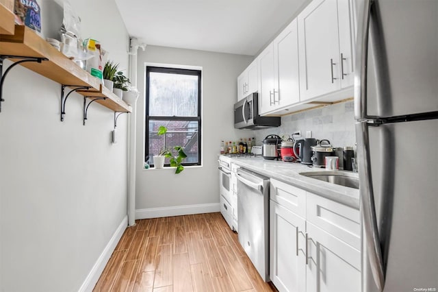 kitchen featuring white cabinets, stainless steel appliances, light hardwood / wood-style flooring, and light stone countertops