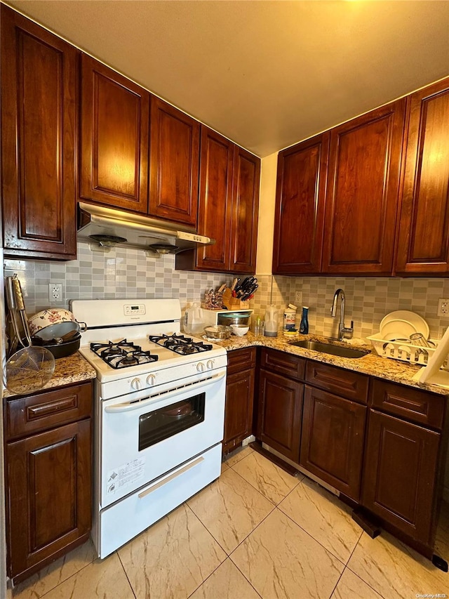 kitchen featuring light stone countertops, white gas range, sink, and tasteful backsplash