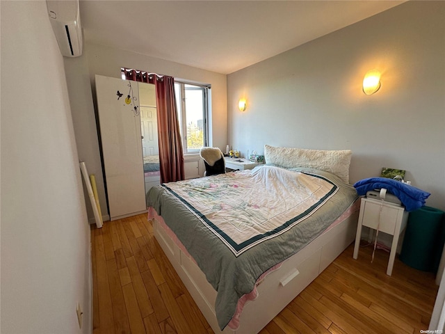 bedroom with light hardwood / wood-style flooring and a wall mounted AC