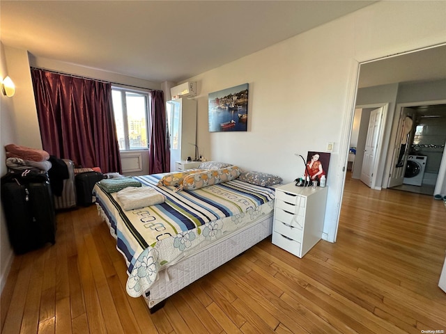 bedroom featuring hardwood / wood-style floors, a wall mounted air conditioner, and washer / clothes dryer