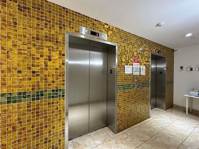 hall with tile walls and elevator