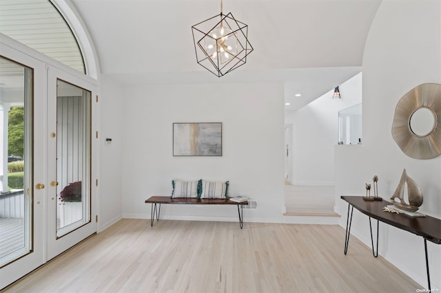 entrance foyer with a notable chandelier, french doors, light hardwood / wood-style flooring, and vaulted ceiling