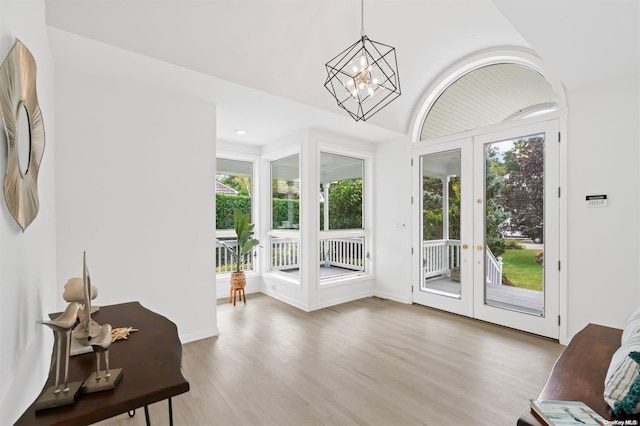 doorway to outside featuring a wealth of natural light, french doors, a chandelier, and hardwood / wood-style flooring