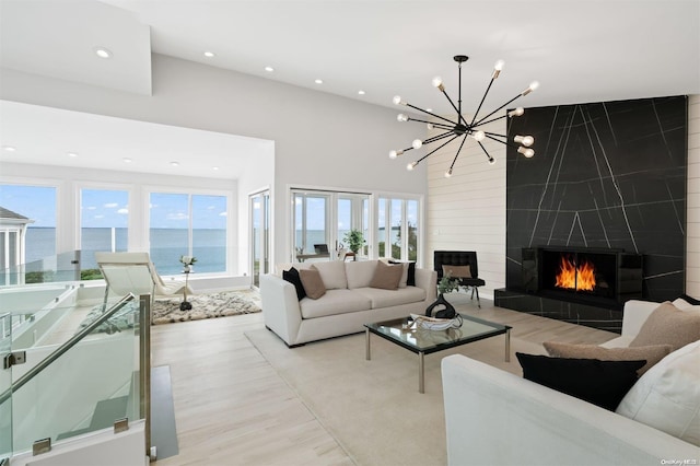 living room featuring a fireplace, a water view, plenty of natural light, and light hardwood / wood-style floors