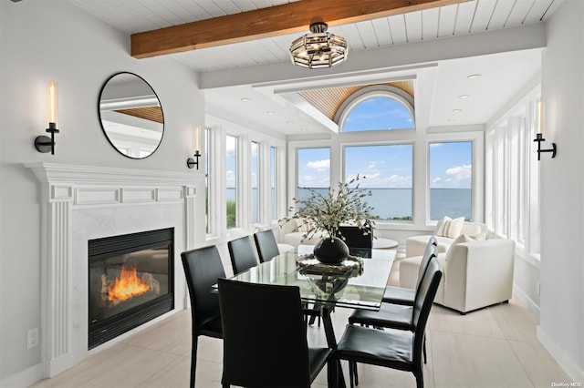 tiled dining area with beam ceiling, a water view, wooden ceiling, and a high end fireplace