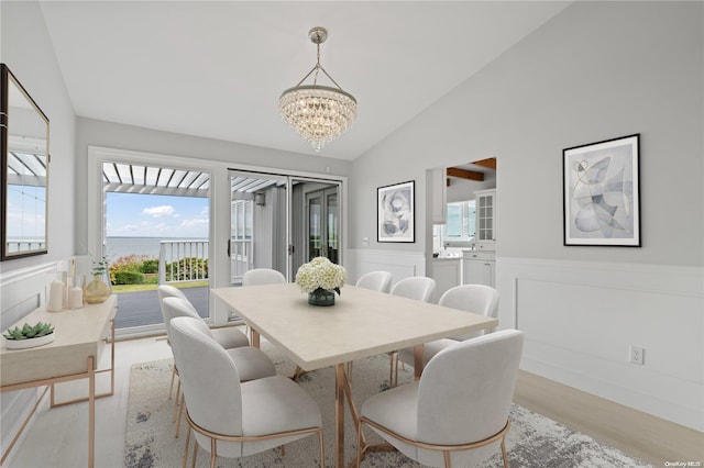 dining area with light wood-type flooring, lofted ceiling, and a notable chandelier