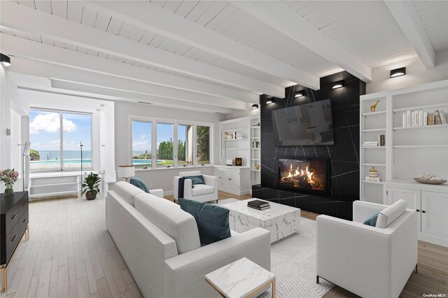 living room featuring a water view, hardwood / wood-style flooring, beamed ceiling, wood ceiling, and a tiled fireplace