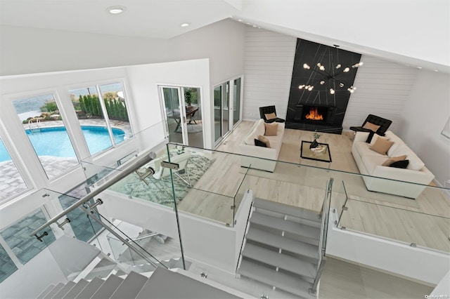 living room with wood walls, a fireplace, and high vaulted ceiling