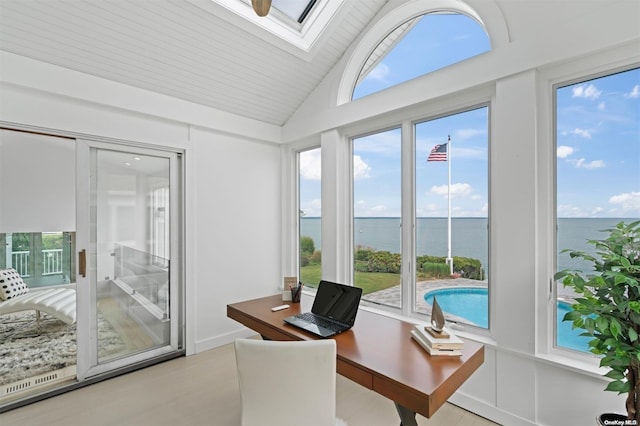 office area with plenty of natural light, a water view, lofted ceiling with skylight, and light hardwood / wood-style flooring