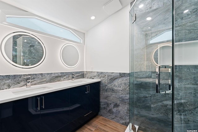 bathroom featuring hardwood / wood-style floors, lofted ceiling, a shower with door, vanity, and tile walls