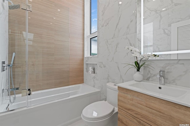 full bathroom featuring vanity, toilet, bath / shower combo with glass door, and tile walls