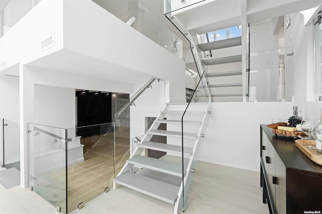 stairway featuring a towering ceiling and hardwood / wood-style flooring