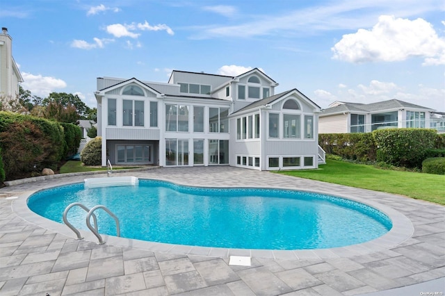 view of pool with a lawn and a sunroom