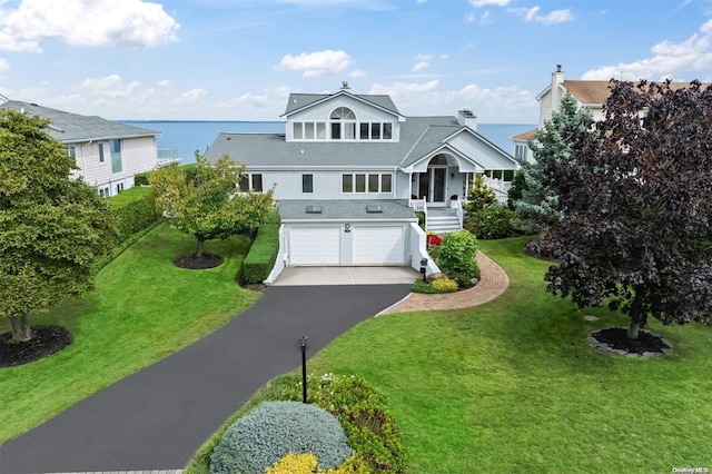 view of front facade with a garage, a water view, and a front lawn