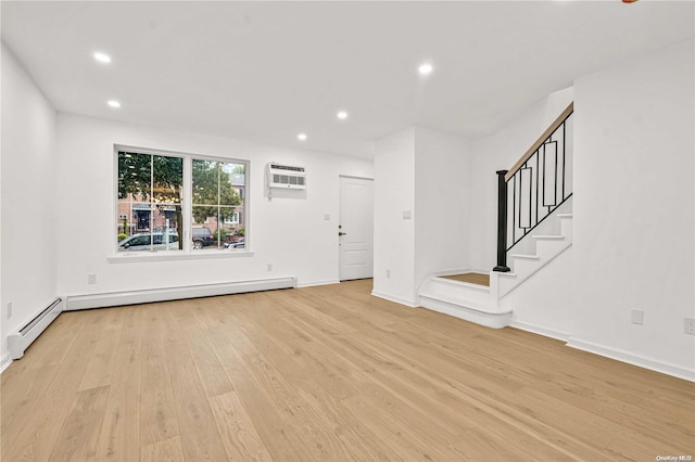 unfurnished living room with light wood-type flooring, baseboard heating, and an AC wall unit