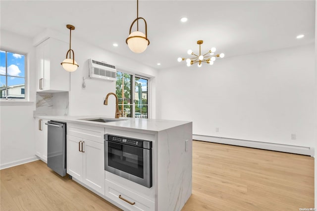 kitchen featuring pendant lighting, light wood-type flooring, white cabinetry, and sink