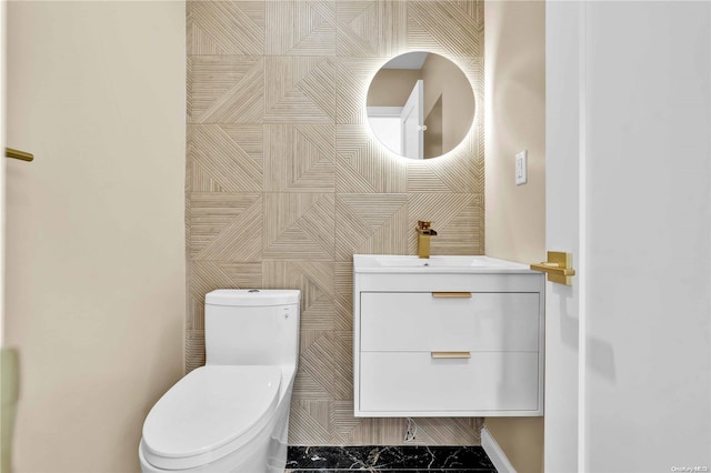 bathroom with vanity, toilet, and tile walls