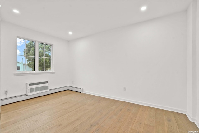 unfurnished room featuring baseboard heating, a wall unit AC, and light hardwood / wood-style floors