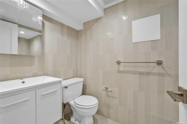 bathroom with vanity, toilet, and tile walls