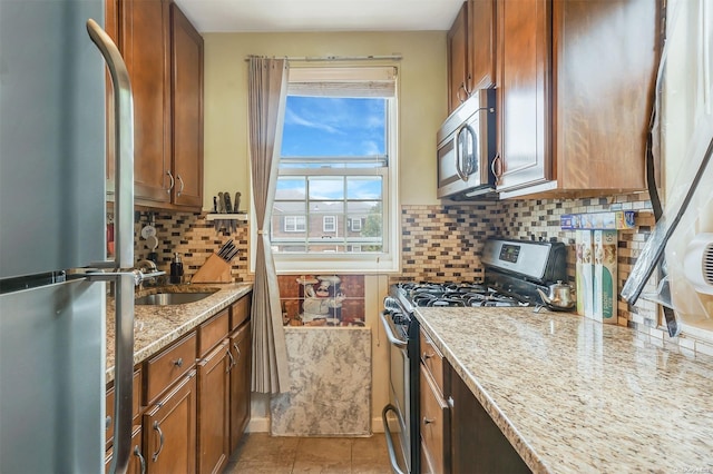 kitchen with light stone countertops, sink, stainless steel appliances, backsplash, and light tile patterned floors