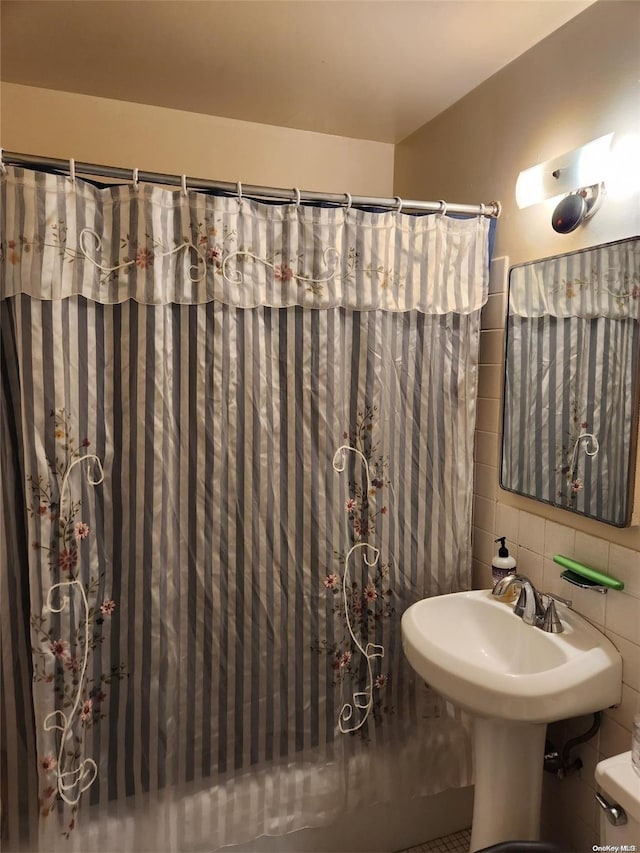 bathroom featuring a shower with shower curtain, toilet, and tile walls