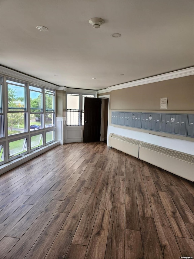 empty room featuring mail boxes, hardwood / wood-style flooring, and crown molding